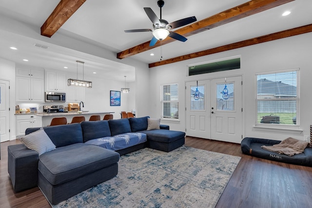 living room with beam ceiling, ceiling fan, dark hardwood / wood-style flooring, and a healthy amount of sunlight