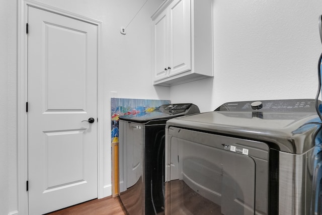 laundry room with cabinets, hardwood / wood-style floors, and washing machine and clothes dryer