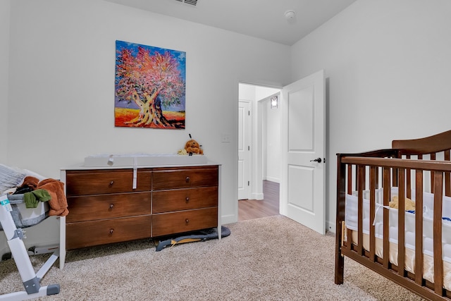 bedroom with light carpet and a nursery area