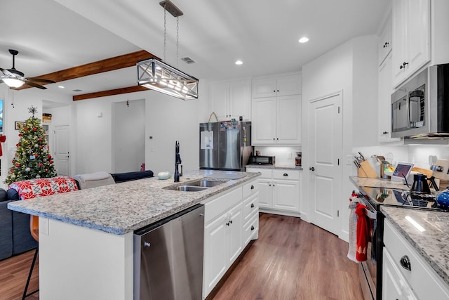 kitchen featuring white cabinets, sink, an island with sink, beamed ceiling, and stainless steel appliances