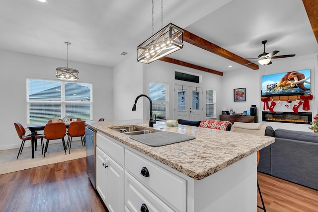 kitchen with sink, stainless steel dishwasher, an island with sink, pendant lighting, and white cabinets