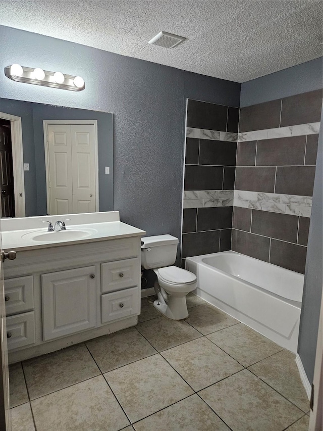 full bathroom featuring toilet, tile patterned flooring, a textured ceiling, and tiled shower / bath