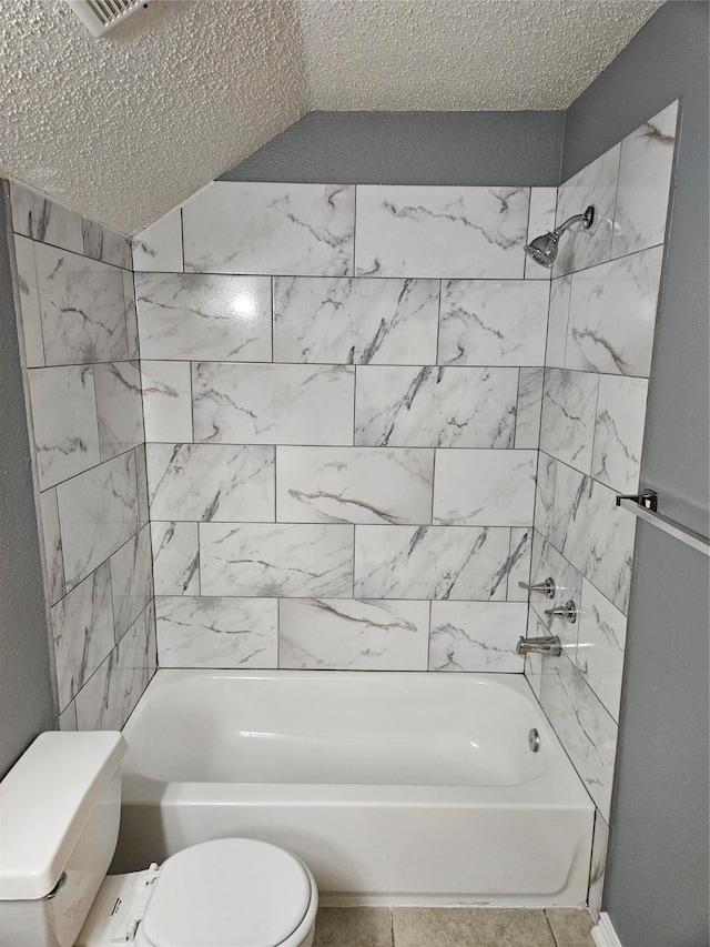 bathroom featuring tile patterned floors, a textured ceiling, toilet, and tiled shower / bath