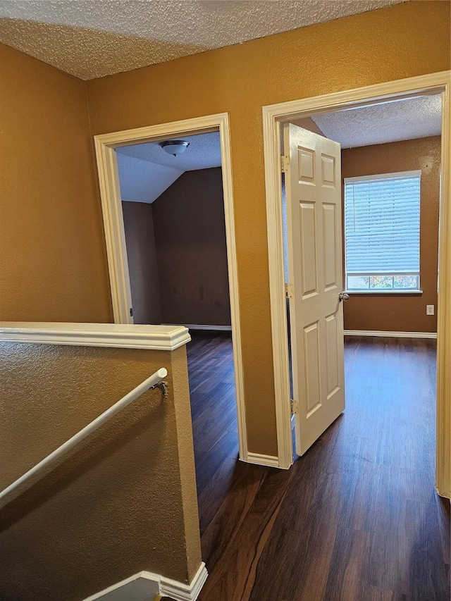 hall featuring dark wood-type flooring and a textured ceiling