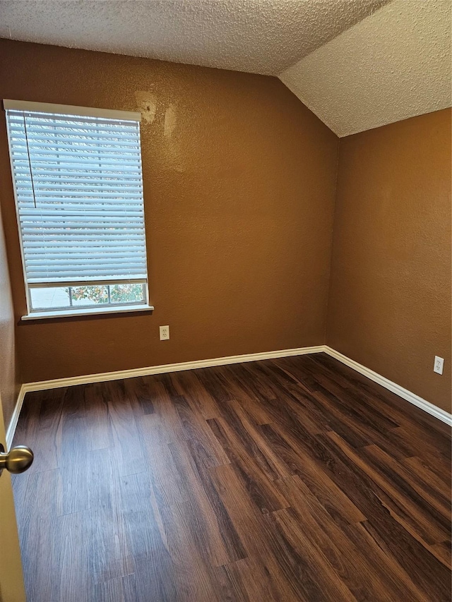 additional living space with a textured ceiling, vaulted ceiling, and dark wood-type flooring