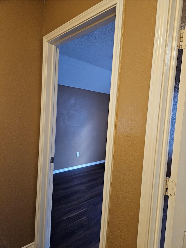 corridor with dark hardwood / wood-style floors and a textured ceiling