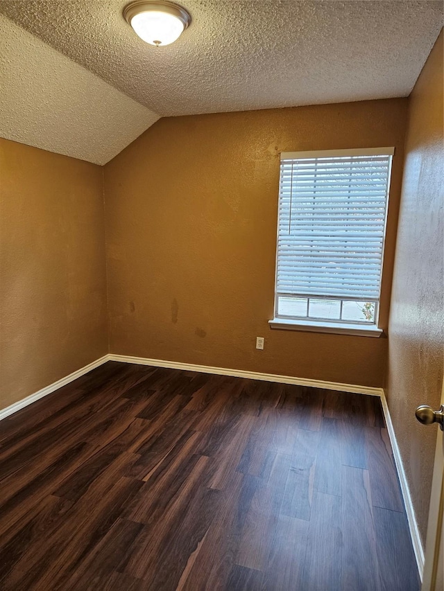 additional living space featuring dark hardwood / wood-style flooring, vaulted ceiling, and a textured ceiling