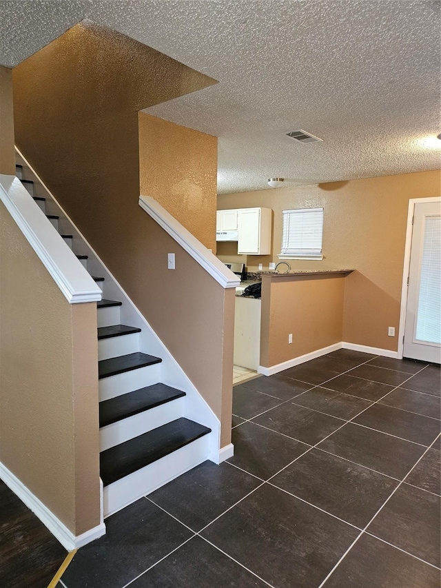 staircase featuring tile patterned flooring and a textured ceiling