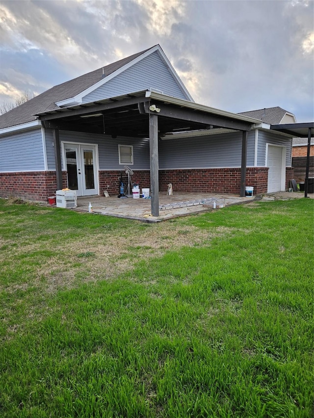 back of property with a garage, a yard, and french doors