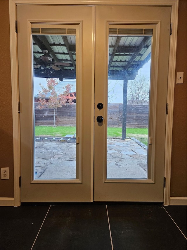 entryway featuring french doors, dark tile patterned floors, and a healthy amount of sunlight