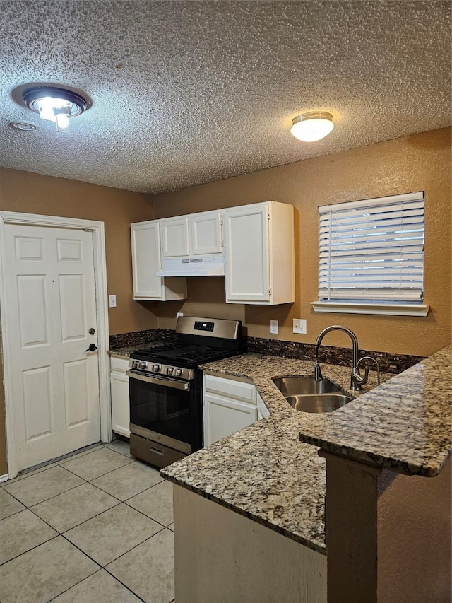 kitchen featuring kitchen peninsula, gas range, sink, white cabinetry, and light tile patterned flooring