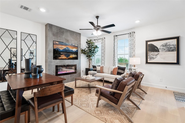 living room with ceiling fan, a fireplace, and light hardwood / wood-style floors