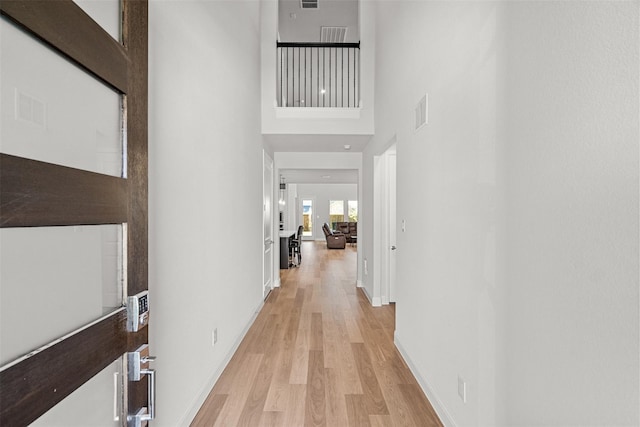 hall featuring a high ceiling and light hardwood / wood-style flooring