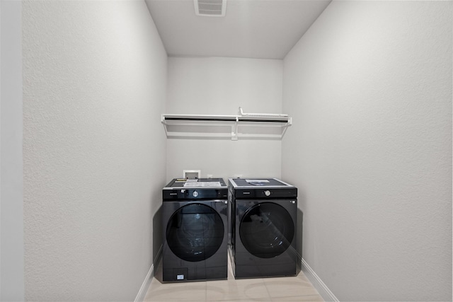 clothes washing area featuring light tile patterned floors and separate washer and dryer