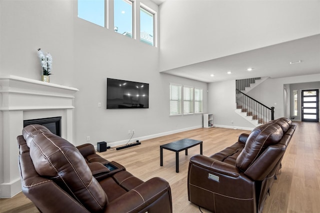 living room featuring a towering ceiling, light hardwood / wood-style floors, and a wealth of natural light