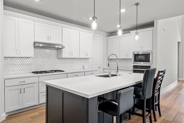 kitchen with sink, stainless steel appliances, light hardwood / wood-style flooring, a kitchen island with sink, and white cabinets