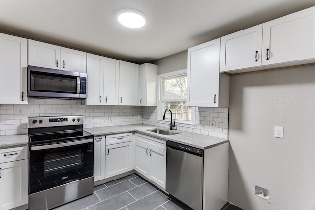 kitchen with appliances with stainless steel finishes, tasteful backsplash, white cabinetry, and sink