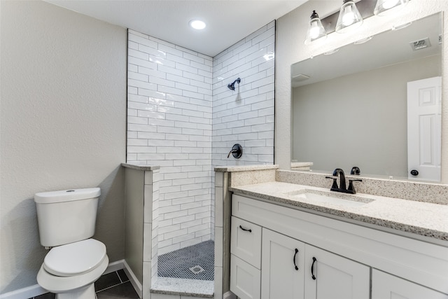 bathroom featuring tile patterned flooring, toilet, vanity, and tiled shower