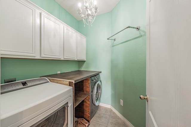 laundry area with light tile patterned flooring, cabinets, an inviting chandelier, and washer and dryer