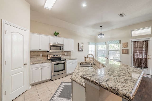 kitchen with pendant lighting, sink, white cabinetry, stainless steel appliances, and an island with sink