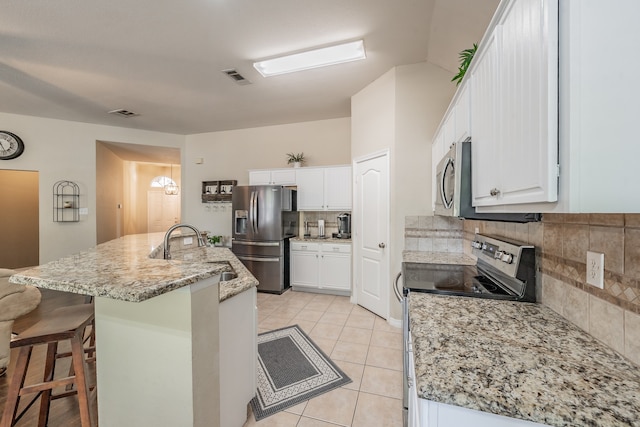 kitchen with stainless steel appliances, sink, a breakfast bar area, and white cabinets