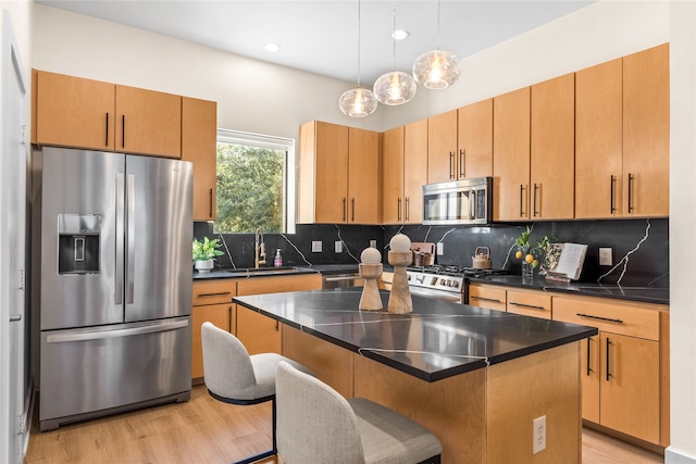 kitchen with sink, a kitchen breakfast bar, a kitchen island, stainless steel appliances, and light hardwood / wood-style floors