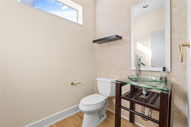 bathroom featuring tile walls, sink, hardwood / wood-style flooring, and toilet