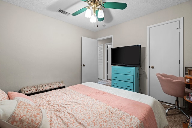 carpeted bedroom featuring ceiling fan and a textured ceiling