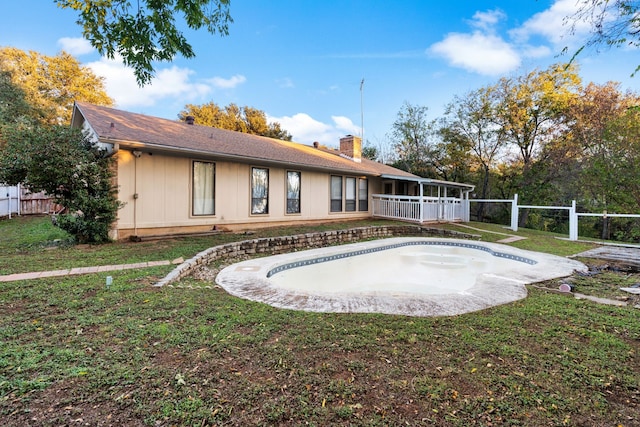 rear view of house with a yard and an empty pool