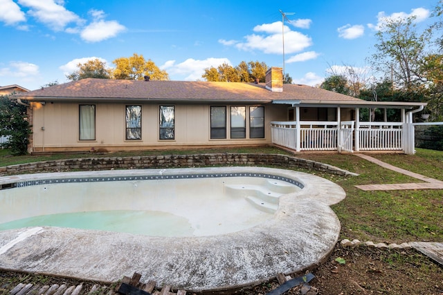 rear view of house with an empty pool