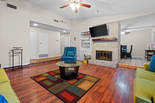 living room featuring a brick fireplace, a textured ceiling, ceiling fan, hardwood / wood-style flooring, and lofted ceiling