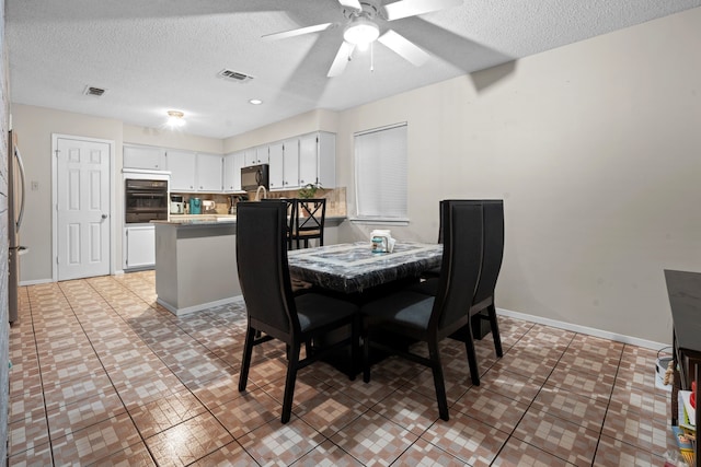 dining area featuring tile patterned flooring, a textured ceiling, and ceiling fan