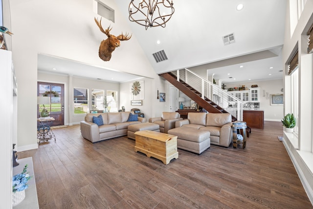 living area featuring dark wood-style floors, a towering ceiling, visible vents, and a notable chandelier