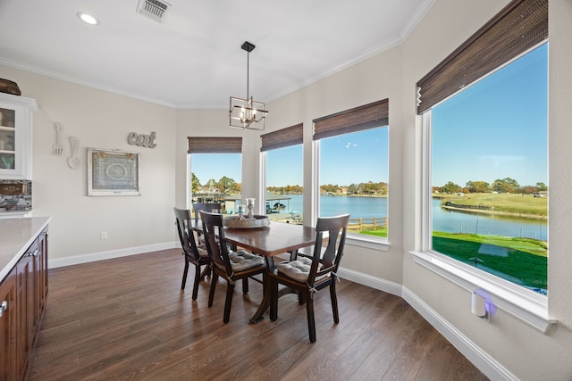 dining room featuring plenty of natural light, visible vents, ornamental molding, dark wood-type flooring, and a water view