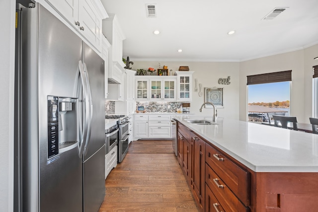 kitchen with appliances with stainless steel finishes, visible vents, a sink, and ornamental molding