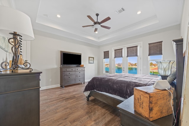 bedroom featuring access to exterior, a raised ceiling, visible vents, wood finished floors, and baseboards