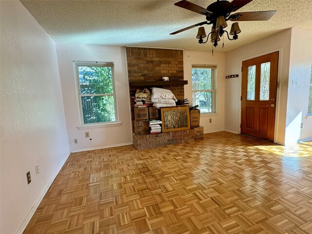 unfurnished living room featuring ceiling fan, a textured ceiling, and light parquet flooring