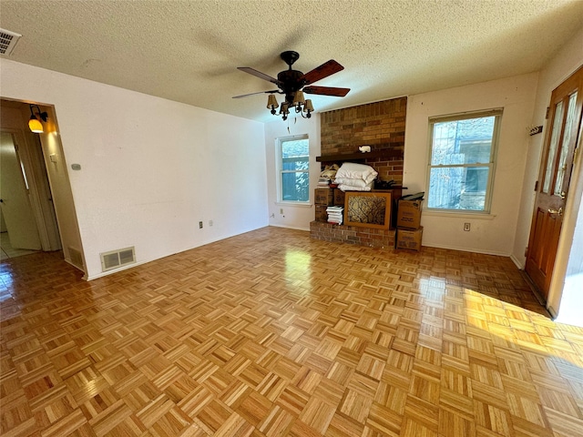 unfurnished living room with ceiling fan, light parquet floors, and a textured ceiling