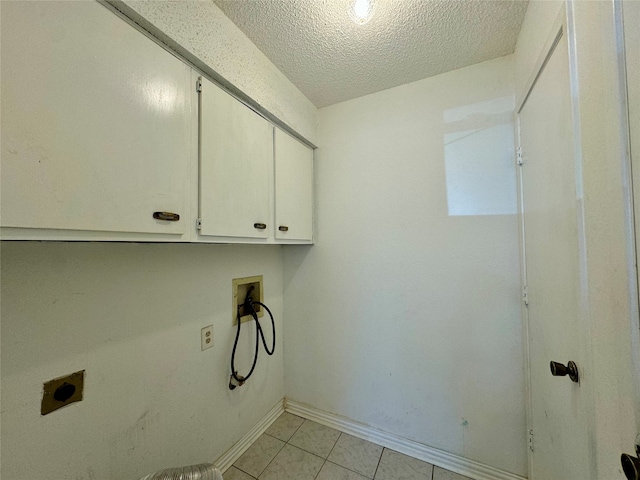 washroom with electric dryer hookup, cabinets, washer hookup, light tile patterned floors, and a textured ceiling