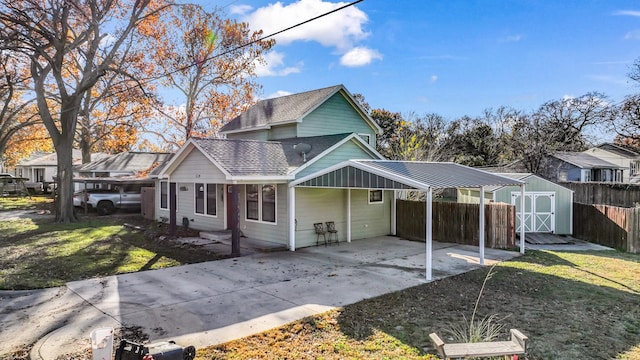 view of front of property featuring a front yard, a carport, and a storage shed