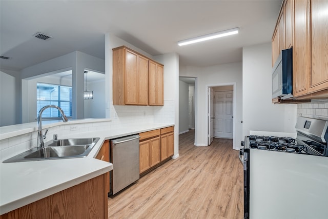 kitchen with dishwasher, backsplash, sink, light hardwood / wood-style flooring, and gas range oven