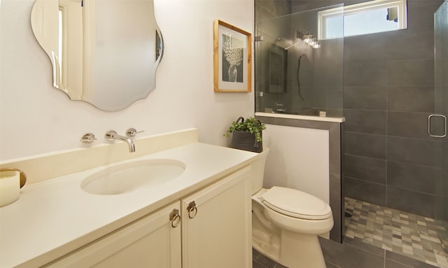 bathroom with tile patterned floors, vanity, toilet, and a tile shower