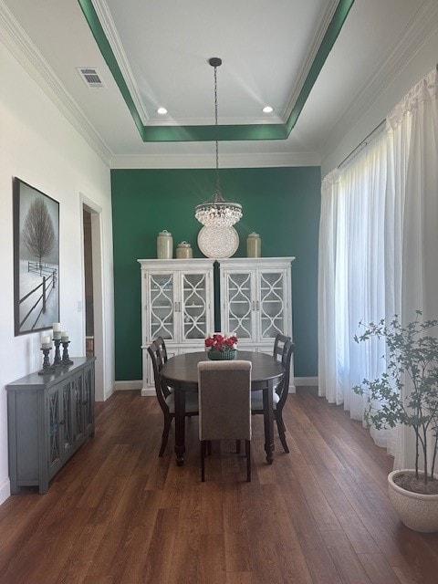 dining area featuring a raised ceiling, a notable chandelier, dark hardwood / wood-style floors, and ornamental molding