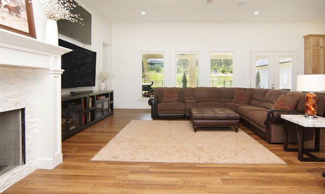 living room featuring hardwood / wood-style flooring, crown molding, a fireplace, and french doors