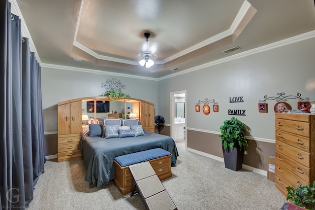 carpeted bedroom featuring a tray ceiling, ensuite bathroom, ceiling fan, and ornamental molding