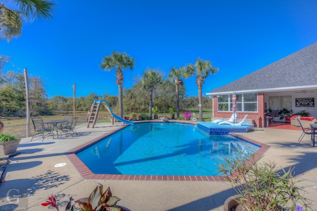 view of pool featuring an in ground hot tub, a water slide, and a patio