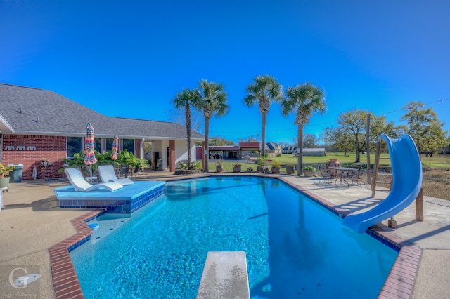 view of swimming pool with a patio area, a diving board, and a water slide