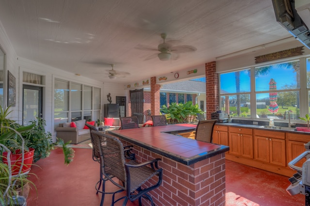 view of patio with ceiling fan, area for grilling, and an outdoor wet bar