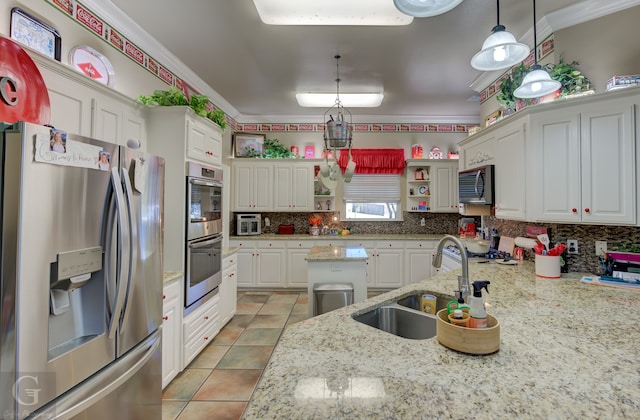 kitchen featuring appliances with stainless steel finishes, decorative light fixtures, sink, white cabinets, and light stone countertops