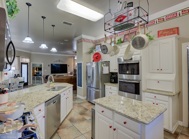 kitchen with white cabinetry, sink, stainless steel appliances, crown molding, and a center island with sink